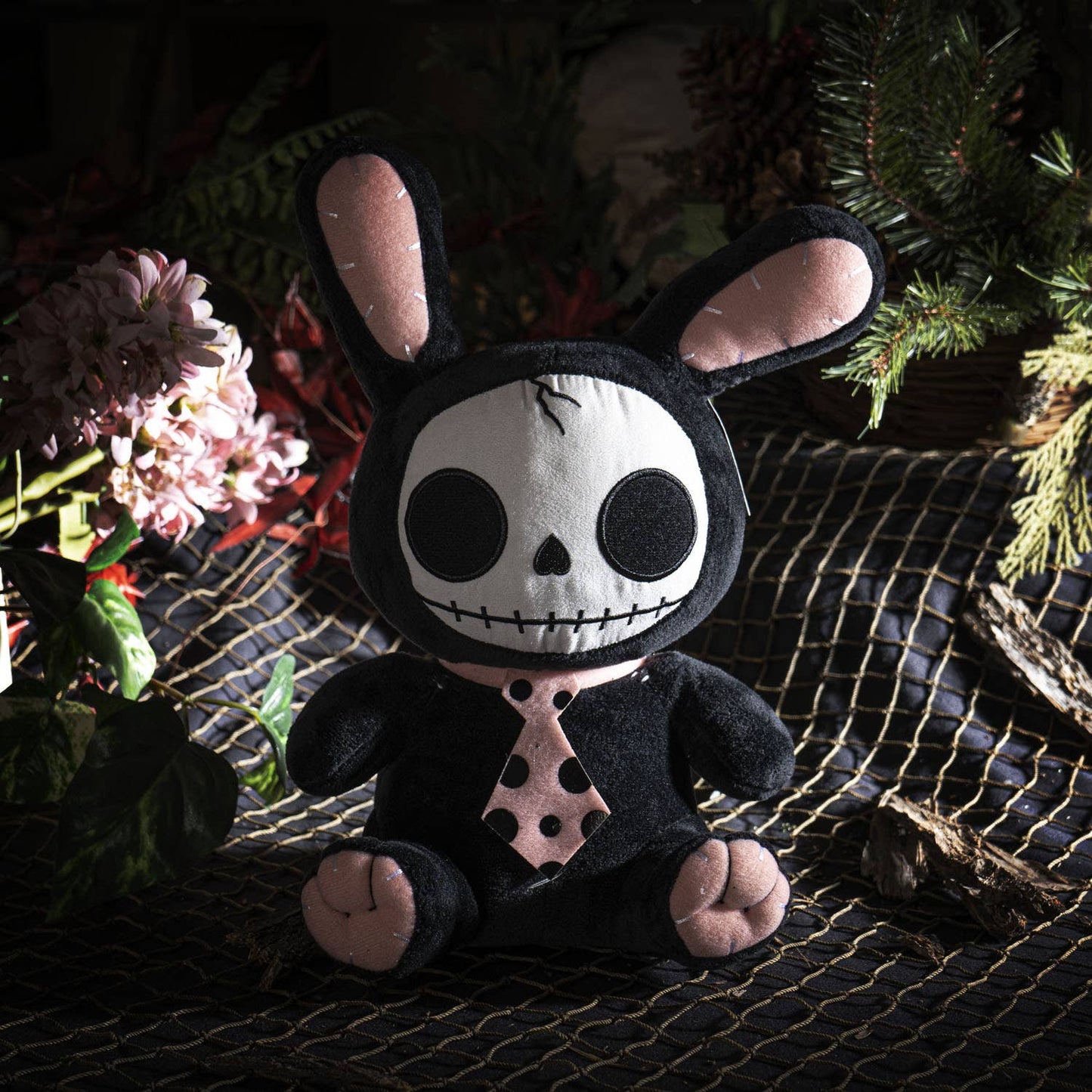 Black plush bunny with skull face, pink inner ears, and polka-dot tie detail.