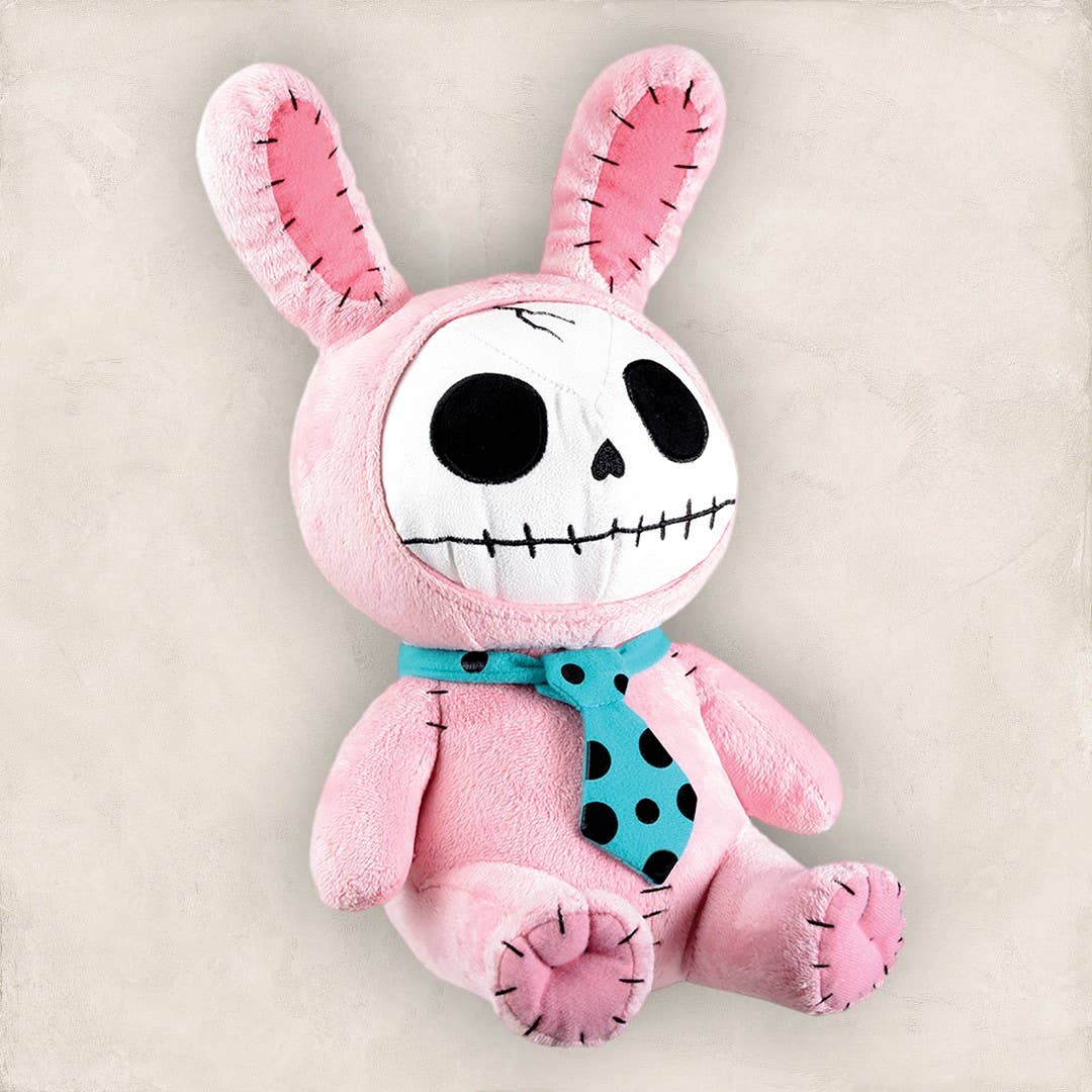 Pink bunny plush with skull face, black stitched eyes and mouth, wearing a blue polka dot tie.