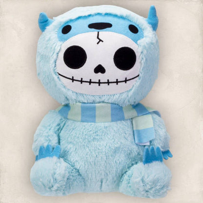 Blue furry plush with skull face and small horns wearing striped scarf.